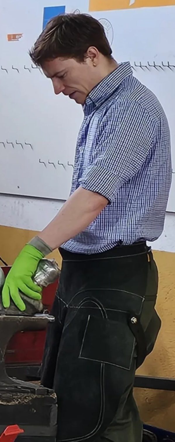 Hombre con guantes verdes trabajando en un taller, concentrado en una tarea.